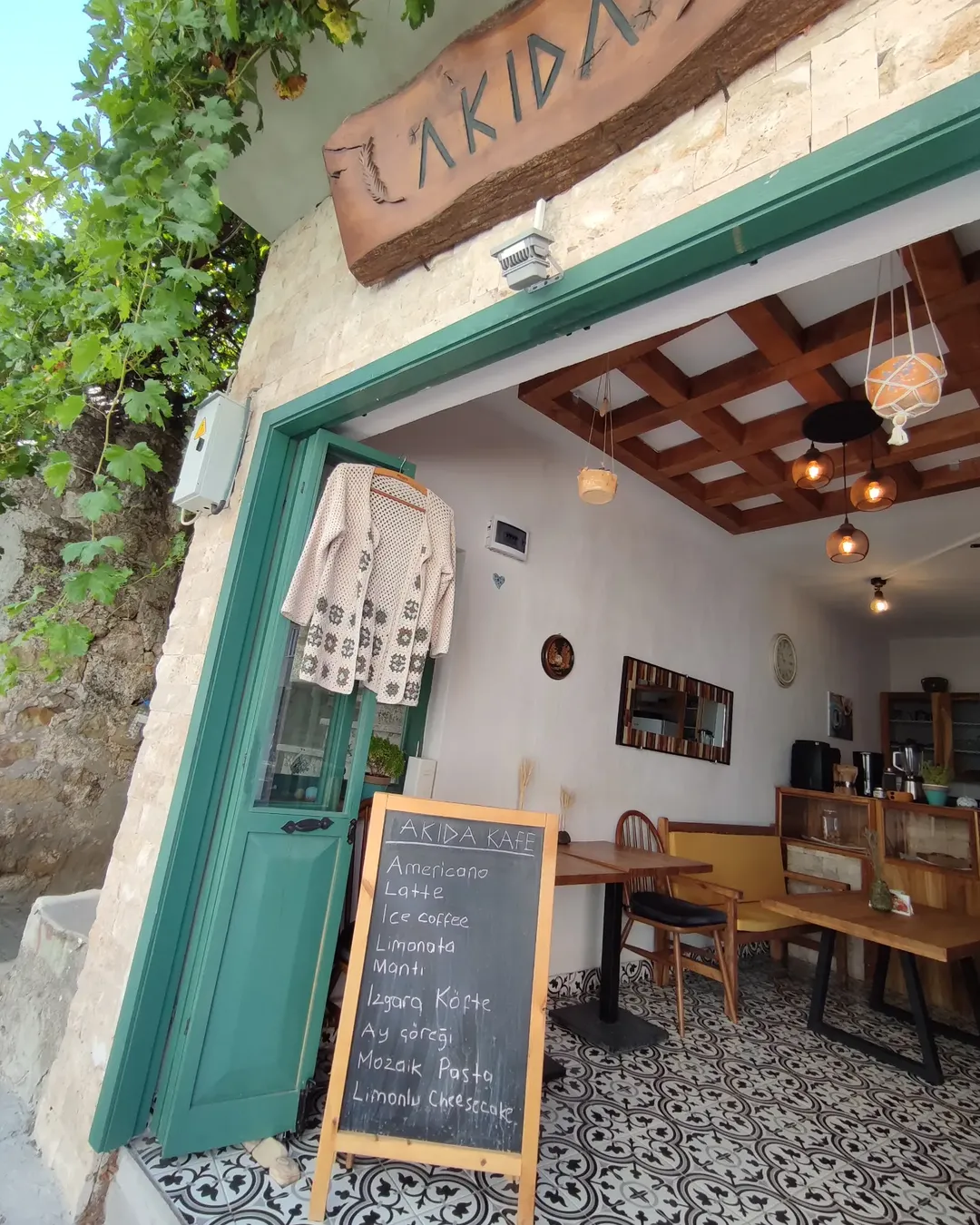 Çanakkale’deki Akida Kafe’nin açık giriş cephesi, kara tahta menüsü ve sıcak iç mekan görünümü